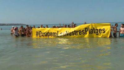 Overtourism protesters take over popular Mallorca beach demanding controls on visitor numbers - euronews.com